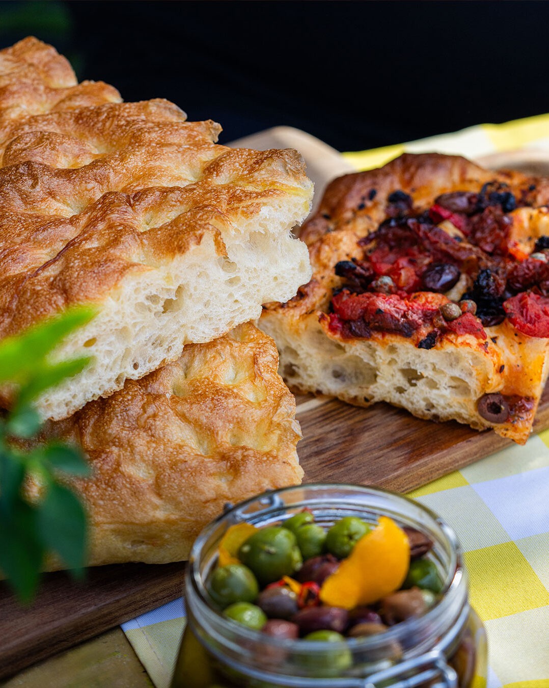 La focaccia est un classique invétéré des étés italiens. Bon, c’est vrai qu’on en mange avec grand plaisir à l’année, mais la joie de mordre dans un morceau de focaccia bien goûteuse à la plage ou lors des pique-niques al fresco assure une joie décuplée. La focaccia est un peu la cousine de la pâte pizza, et comme sa complice tomatée, elle se laisse transformer presque à l’infini. Romarin, sauge, fromage ou oignons? Oh que oui. Raisins secs, zeste d’agrumes et cannelle? Pourquoi pas! Avec cette recette de base infaillible, vous pourrez laisser votre imagination vagabonder et mettre en vedette les produits de saison qui vous font envie, comme les belles tomates cerises et les olives qu’on a choisies pour celle-ci. Un délice incontournable à ajouter à votre arsenal!